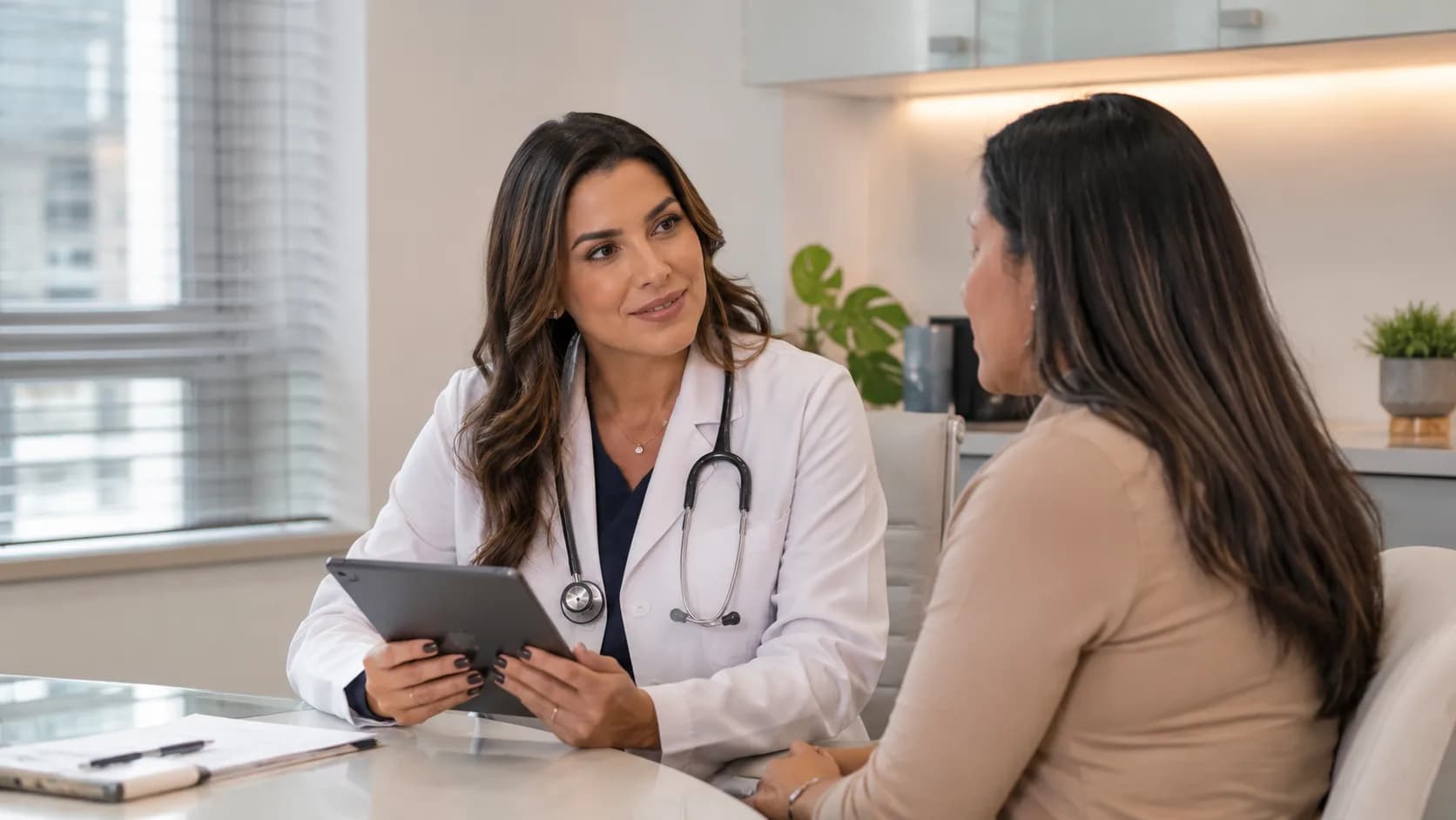 Médica conversando com uma paciente, segurando um tablet.